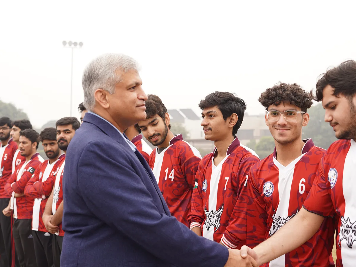 Students in sports uniforms greeting a campus official.