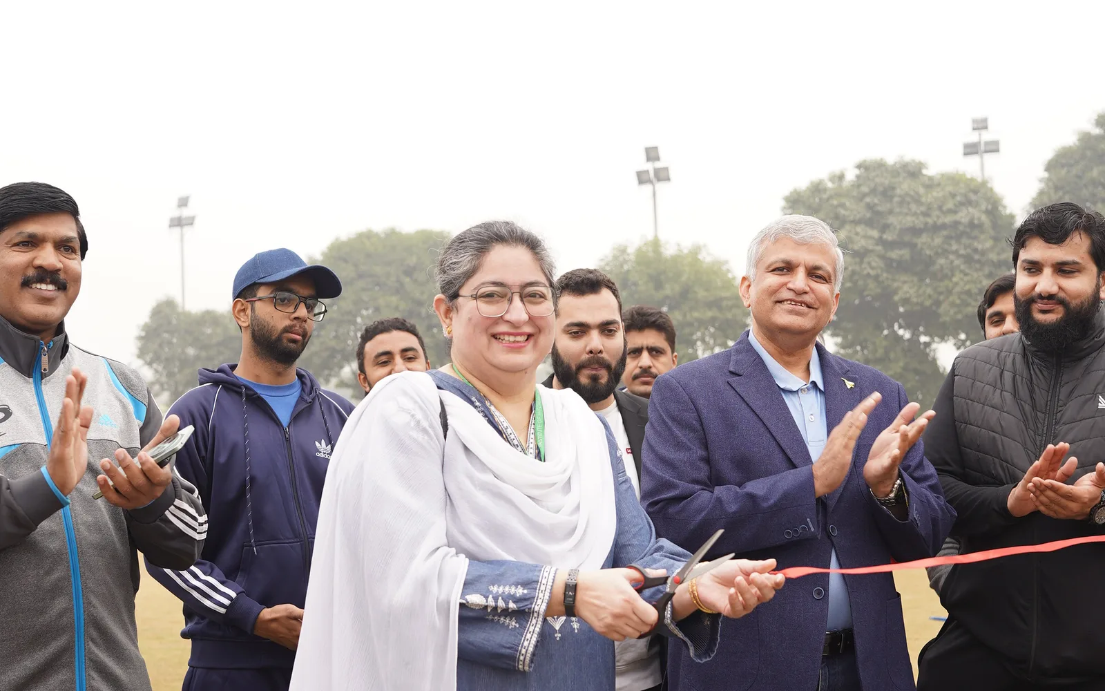 Campus staff cutting a ceremonial ribbon at a sports event.