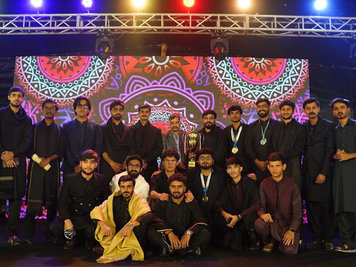 A student society team gathered on stage with a trophy.
